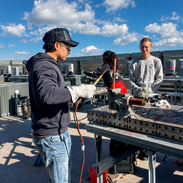 An HVAC student uses a torch while practicing hands-on installation skills in the Skilled Trades Center lab