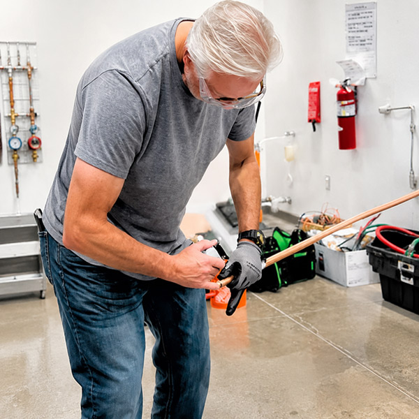An HVAC student practices joining copper pipe in the lab