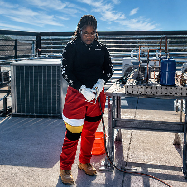 An HVAC student works safely with rooftop equipment