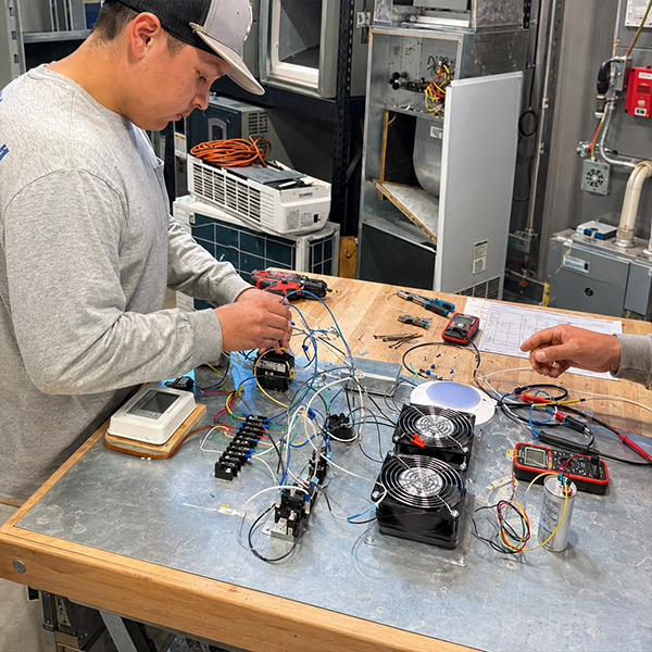An HVAC student troubleshoots an electrical circuit board